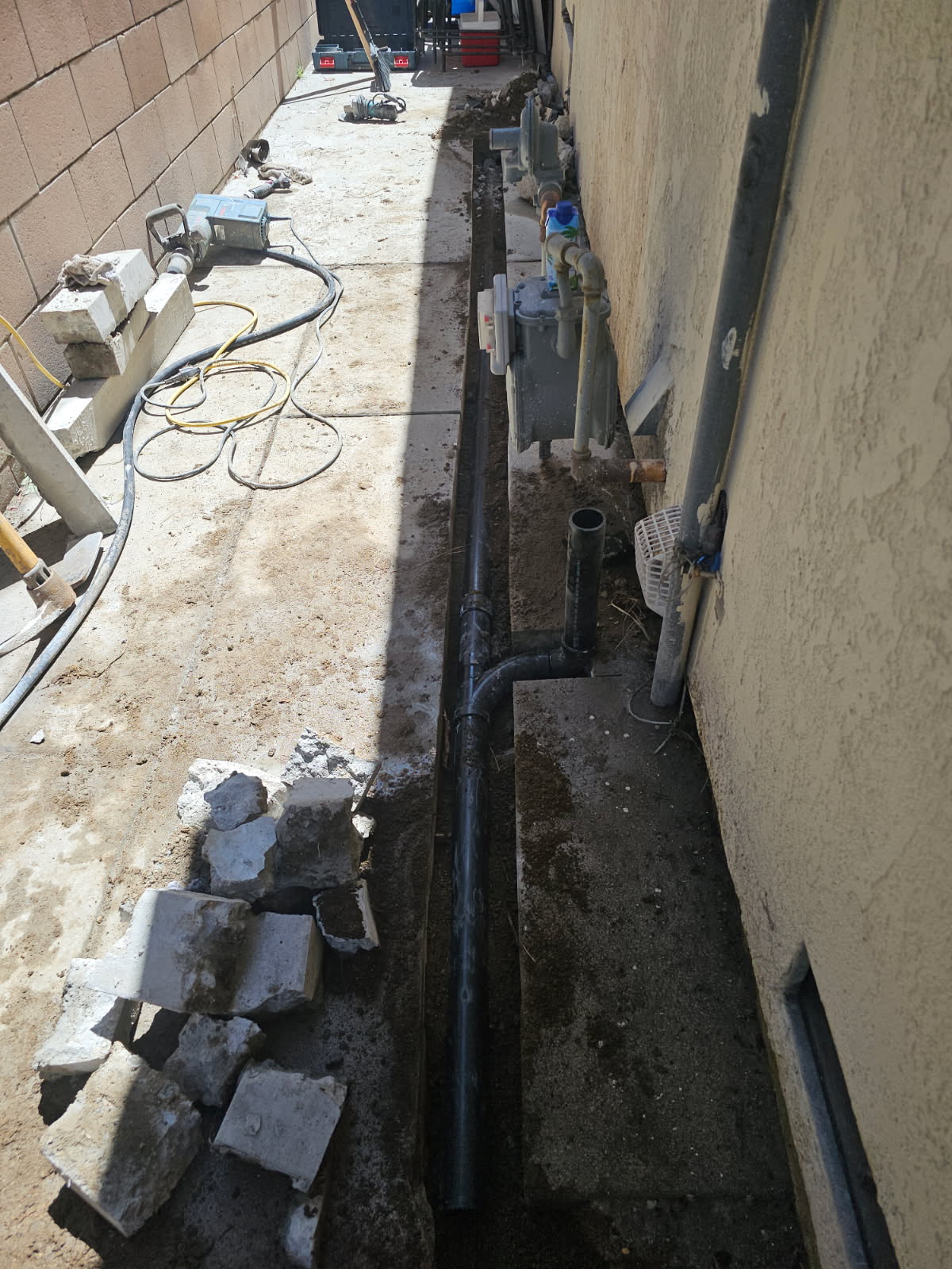 Open excavation showing replaced ABS sewer line running along a stucco home exterior